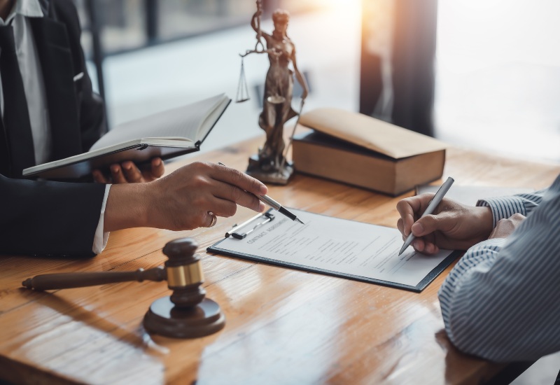 Two Individuals Reviewing a Legal Document with a Gavel on the Table in Tucson, AZ & Pima County 